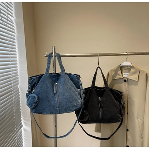 Detail of large denim tote bag featuring a round coin purse and adjustable straps