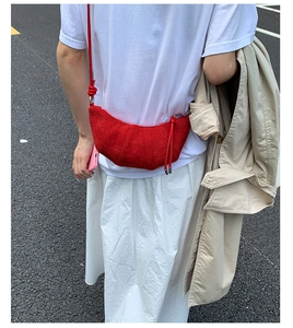 Détail d'un sac croissant en daim rouge avec texture matelassée et fermeture éclair en métal