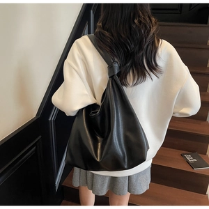 Detail of the knotted shoulder strap on a black large capacity soft leather tote bag
