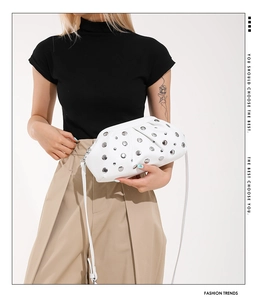 Détail du sac nuage blanc avec rivets argentés et bandoulière amovible sous lumière studio