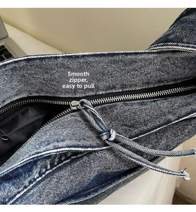 Detailed macro view of the silver metal zipper and denim tie puller on the tote bag