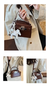 Detail of brown croc-embossed leather handbag featuring a white horse charm and pearl chain