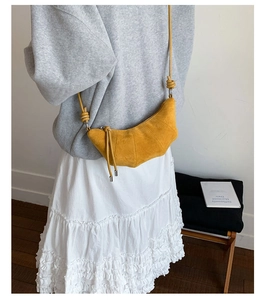 Détail du sac croissant jaune avec bandoulière nouée et fini mat sur le modèle