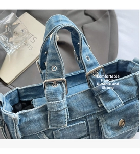 Detailed close-up of blue denim handbag with sturdy handles and metal buckle accents