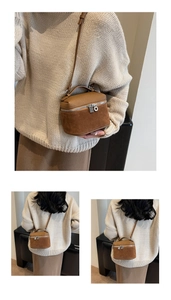 Detail of a brown suede and pebbled leather crossbody box bag with silver zipper
