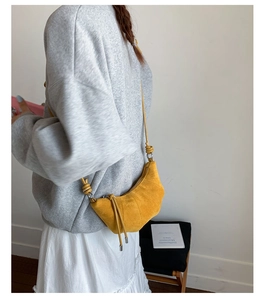 Détail d'un sac croissant en daim jaune avec coutures et fermeture éclair à franges