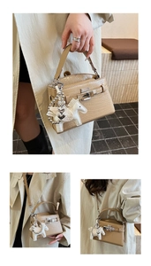 Detail of beige crocodile texture leather bag with metal lock and heart charm