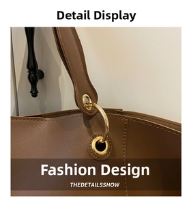 Detail of brown leather tote bag with polished gold metal ring strap connectors