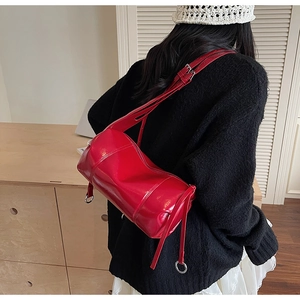 Detail der roten Kissen-Tasche aus glänzendem Leder mit verstellbarem Schultergurt