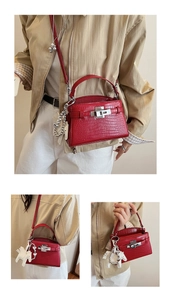 Close-up of red crocodile embossed leather Kelly bag with silver hardware and horse charm