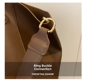 Detail of golden D-ring hardware and pebble grain leather on brown tote bag