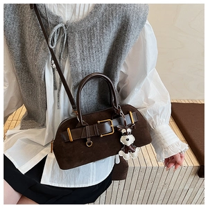 Detail of dark brown suede boston bag with gold hardware and schnauzer dog charm