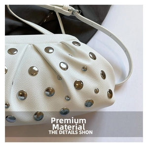 Gros plan sur le cuir grainé blanc et les rivets argentés de ce sac nuage élégant