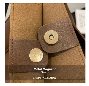 Macro detail of golden magnetic buckle on caramel brown suede and leather tote bag