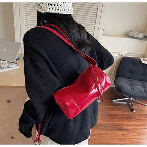 Detail einer stylischen roten Zylindertasche aus Leder, getragen von einem Modell im Haus