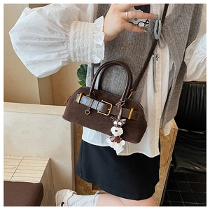 Detail of coffee brown suede handbag with golden hardware and schnauzer charm
