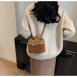 Detailed back view of brown textured leather crossbody box bag with silver hardware on model