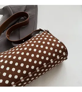 Close-up of brown polka dot boston bag with leather strap and silver buckle detail