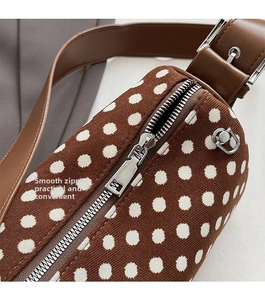 Detailed close-up of smooth silver zipper and leather strap on polka dot pillow bag
