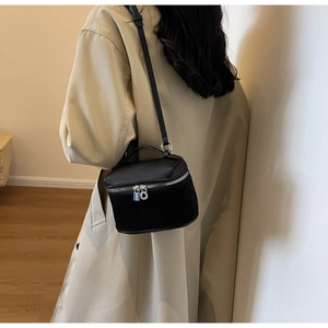 Detail view of a black mini bucket bag featuring a textured lychee grain leather finish