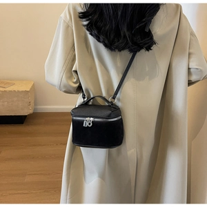 Detail of a black mini crossbody bag featuring a mix of pebbled and suede textures