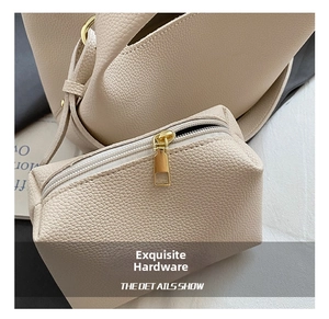 Detail of beige lychee grain leather bucket bag featuring gold-tone metal hardware accessories