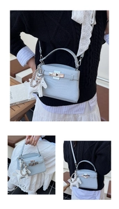 Detailed view of light blue crocodile embossed leather bag with silver lock and horse charm