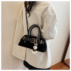 Detail of black suede shell bag featuring a bold belt buckle and Schnauzer dog charm