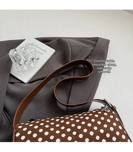 Detail of adjustable silver buckle and brown leather strap on polka dot bag