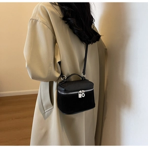 Model wearing a black mini crossbody bag featuring mixed leather and matte suede textures