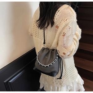 Detail of grey bucket bag with silver metal chain strap and brand lettering