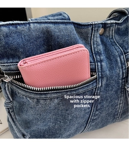 Detailed macro view of the light blue denim bag's zippered pocket and inner storage