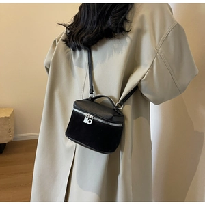 Detail of a mini black crossbody bag with lychee leather and suede patchwork finish