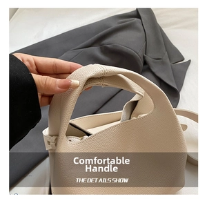 Close-up of soft litchi grain leather handle on minimalist off-white bucket bag