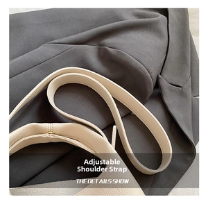 Detail of adjustable litchi grain leather shoulder strap on cream bucket bag