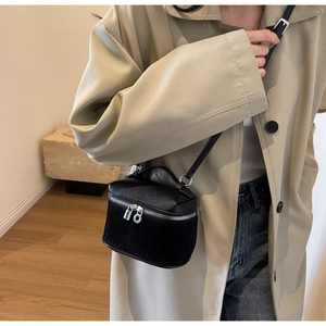 Side view of black matte mini crossbody box bag worn with a stylish beige trench coat