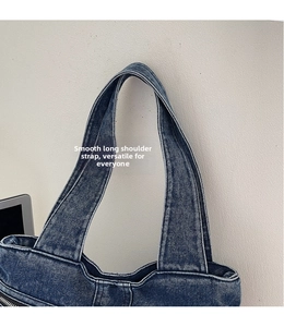 Detail of wide adjustable shoulder strap on blue denim tote bag with zipper closure