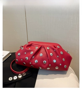 Détail du sac rouge en cuir grainé avec rivets argentés et une bandoulière mince