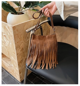 Vue détaillée du sac seau en daim marron avec longues franges et détails argentés