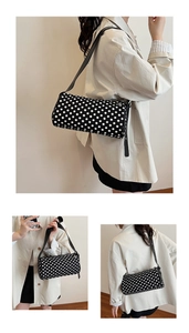 Close-up detail of black and white polka dot cylinder shoulder bag with adjustable strap