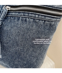 Detail of washed blue denim fabric texture and smooth metal zipper on the tote bag