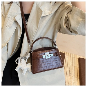 Detail view of brown crocodile-textured handbag with silver clasp and Pegasus charm