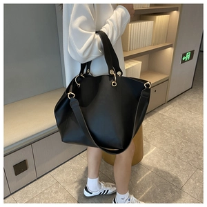 Close-up of a large black leather tote bag featuring elegant golden hardware rings