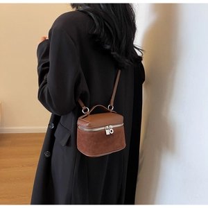 Rear view of model wearing a vintage brown vanity case bag with leather and suede texture