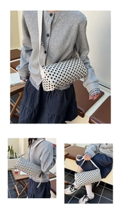 Detailed view of polka dot cylinder pillow bag with adjustable white shoulder strap