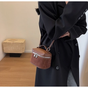 Detail of a brown textured leather and suede mini box bag styled on a black blazer