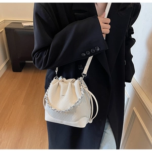 Detail of cream drawstring bucket bag with textured leather and silver chain strap