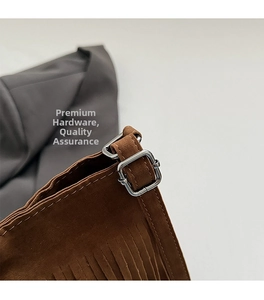Détail de boucle argentée et franges sur un sac seau en daim marron pour femme