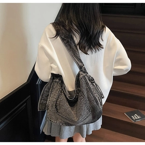 Detailed view of large acid wash denim hobo bag featuring wide strap and vintage grey finish