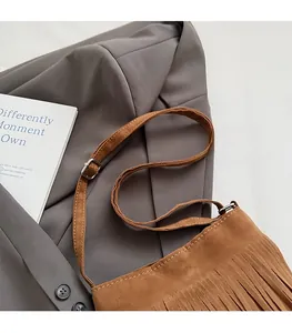 Détail du sac seau en daim marron avec de longues franges et des coutures contrastées
